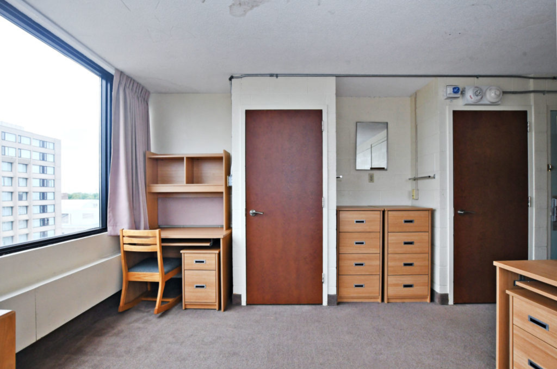 Photo d'une chambre double dans la résidence Stong. Un bureau et une armoire sont visible sur la photo
